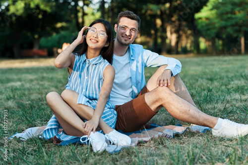 young couple sitting on grass in park © SHOTPRIME STUDIO