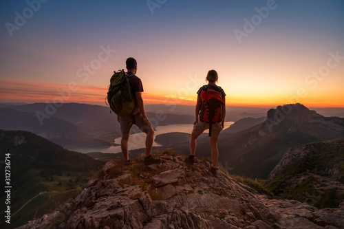 travel to Alps mountains, tourists hikers with backpacks at sunset enjoying panoramic view
