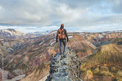adventure travel, hiking in Iceland with backpack, tourist looking at colorful landscape of Landmannalaugar photo