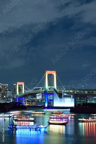 Urban landscape of Tokyo Rainbow bridge with illuminated tourist boats 