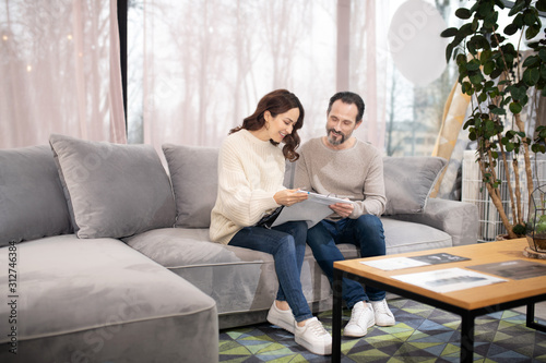 Man and woman in furniture salon sitting on a comfortable sofa