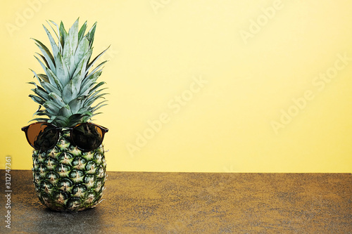 Cool ananas with sunglasses on yellow background