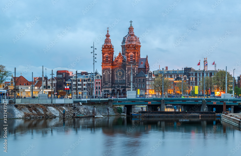 Scenic view of Basilica of Saint Nicholas and skyline of the the old city  district reflected in the water of the canal. Blue hours, Amsterdam, Netherlands.