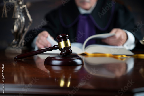 Judge looking through legal code with the wooden gavel in his hand.