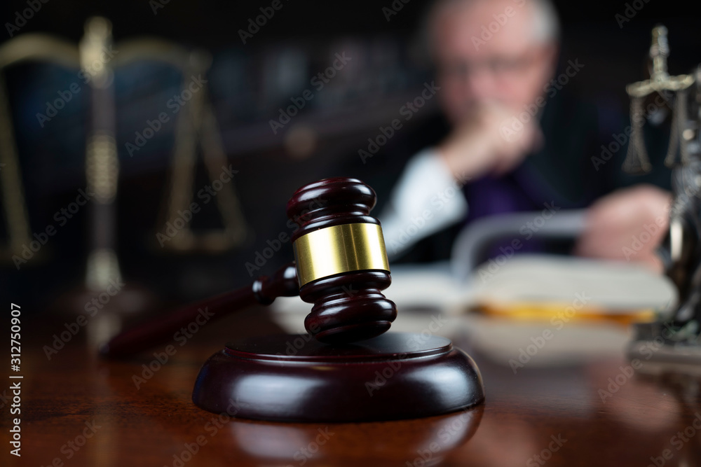 Judge looking through legal code with the wooden gavel in his hand. Judge looking through legal code with the wooden gavel in his hand.