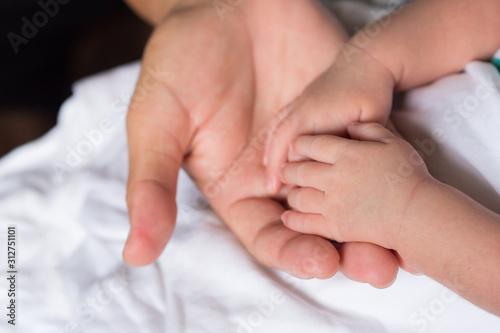 Hands of newborn baby in the hand of mother on white cloth. Close up of baby hands. Space for text. Family concept