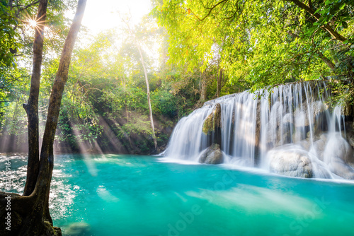 Waterfall and blue emerald water color in Erawan national park with sun light and light ray sunflare, Beautiful nature rock waterfall steps in tropical rainforest at Kanchanaburi province, Thailand