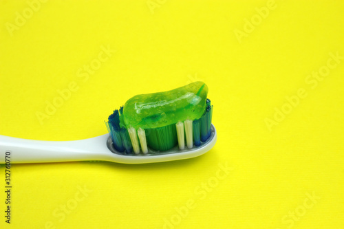 Toothbrush with paste on a yellow background close-up