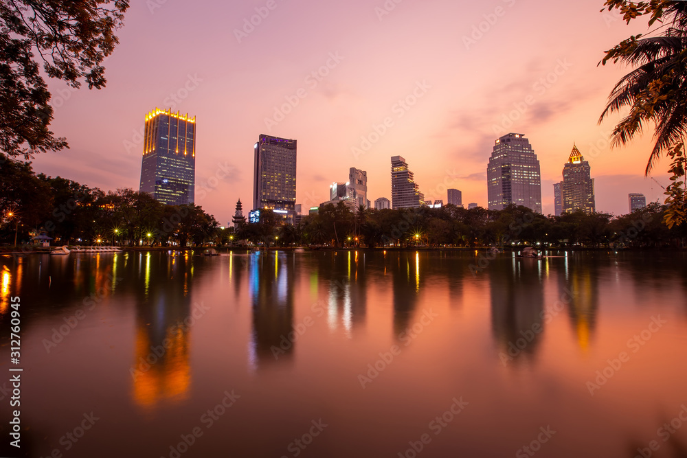 Landscape of the tall building with water reflaction at Lumpini park , Bangkok , Thailand.  The Building in capital of Thailand with sunset at Lumpini park.