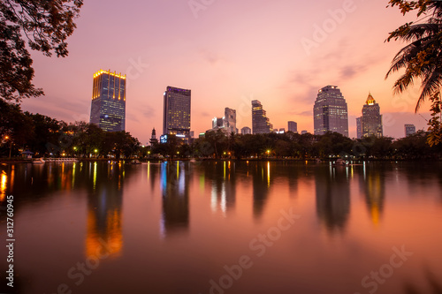 Landscape of the tall building with water reflaction at Lumpini park , Bangkok , Thailand.  The Building in capital of Thailand with sunset at Lumpini park. © witsawat