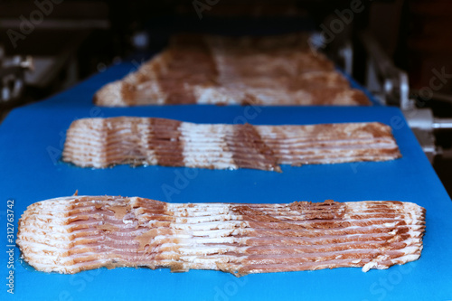 Quadro em tela raw rasher bacon slide ready to pack in packaging on conveyor belt of automation meat slide machine in the food factory
