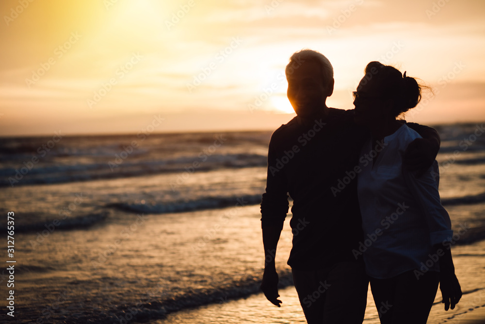 Happy Romantic of senior man laughing while Walking the beach together, on sandy beach during sunset, Retirement age concept and love