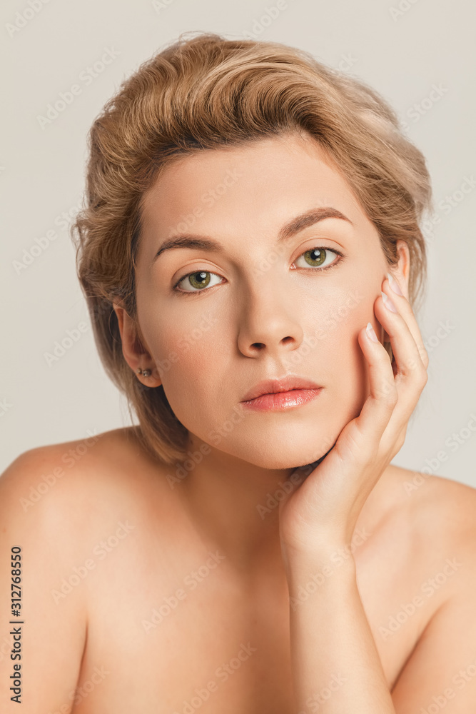 short-haired blonde with green eyes looking at the camera. Hand near face short-haired blonde with green eyes looking at the camera. Hand near face