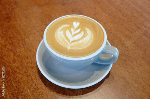A Cup of hot latte art on wooden desk © inspirar