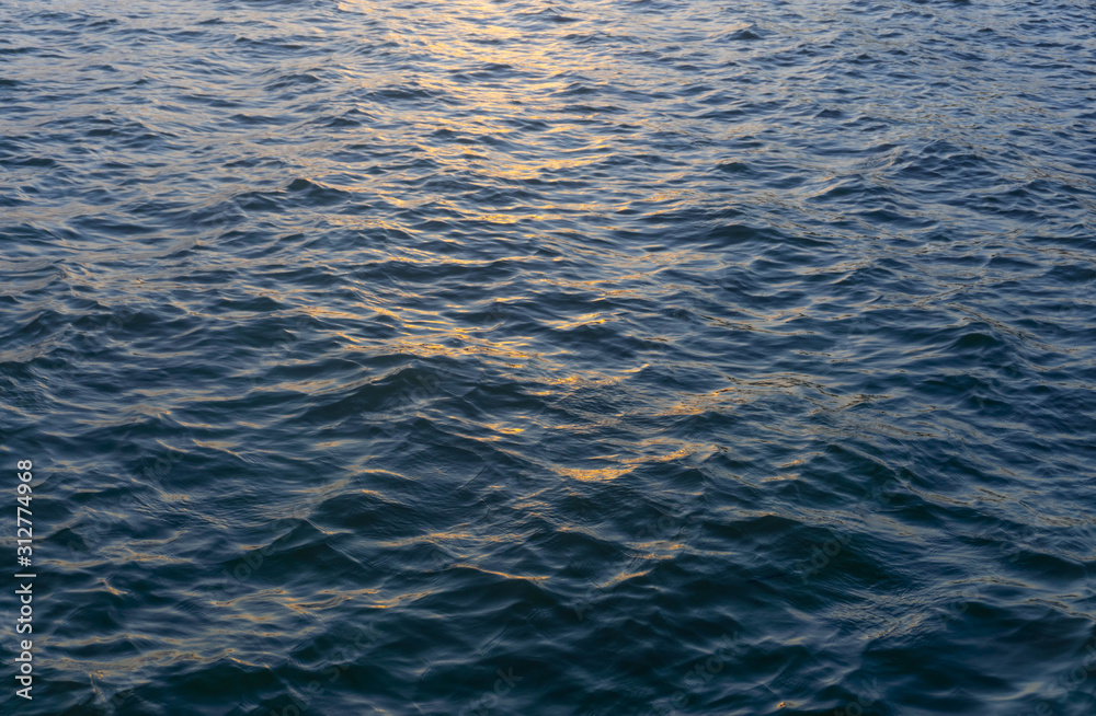 Water ripple surface reflection effect from sunset and sky top view at lake in evening day,wave abstract texture sunlight blue and golden pattern background Water ripple surface reflection effect from sunset and sky top view at lake in evening day,wave abstract texture sunlight blue and golden pattern background