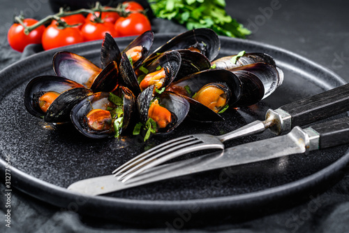 portion of delicious mussels in tomato sauce and parsley. Black background. Top view