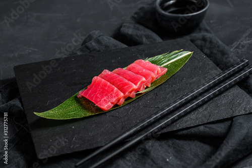 Fresh raw sashimi tuna on a stone Board. Black background. Top view photo