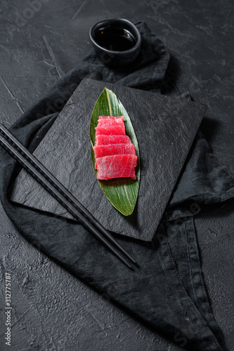 Fresh raw sashimi tuna on a stone Board. Black background. Top view