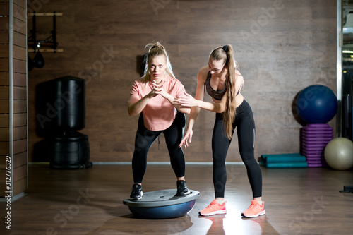 the trainer helps the client to master the bosu training technique photo