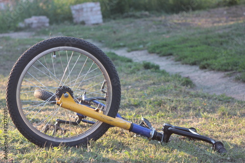 The front wheel of a bmx bicycle lying on the ground on dry grass near the trail