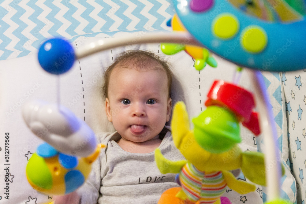 Obraz premium little happy motivated child is playing with dangling rattles, toys for newborn, first toy