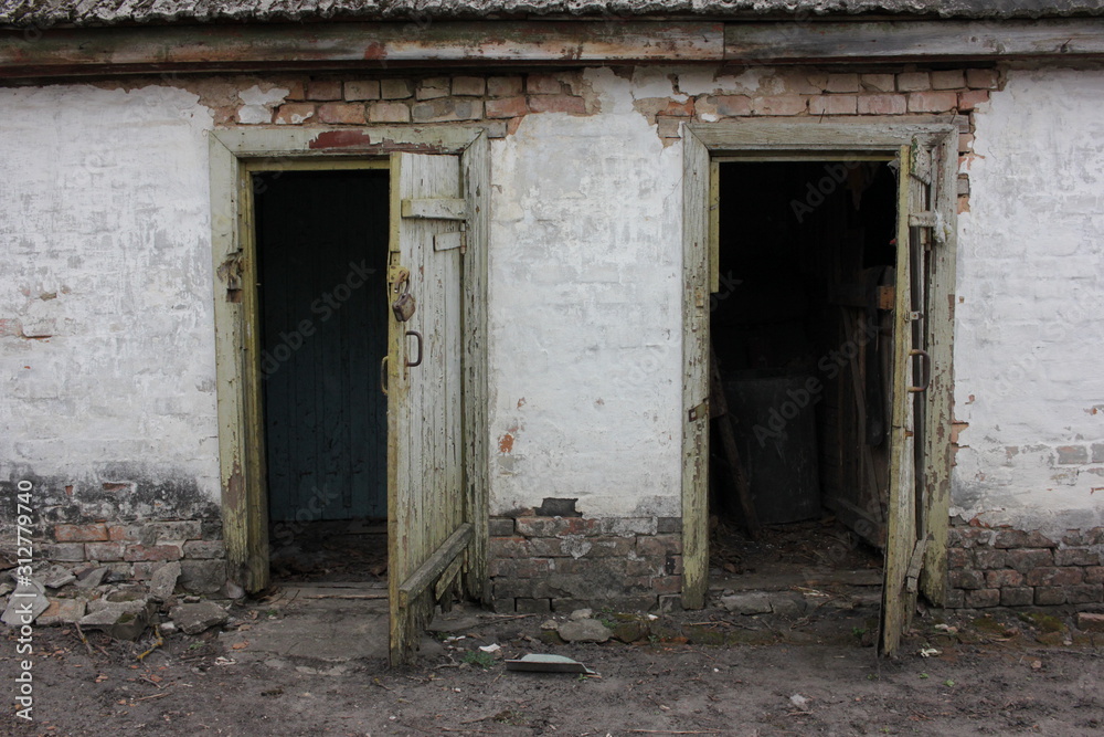 Two old open shabby doors in a white brick farmhouse. Open barn door. Two entrances to the old pantry Two old open shabby doors in a white brick farmhouse. Open barn door. Two entrances to the old pantry