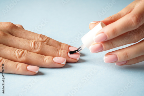 Beautiful hands of a young girl with beautiful manicure on a blue background. French manicure.