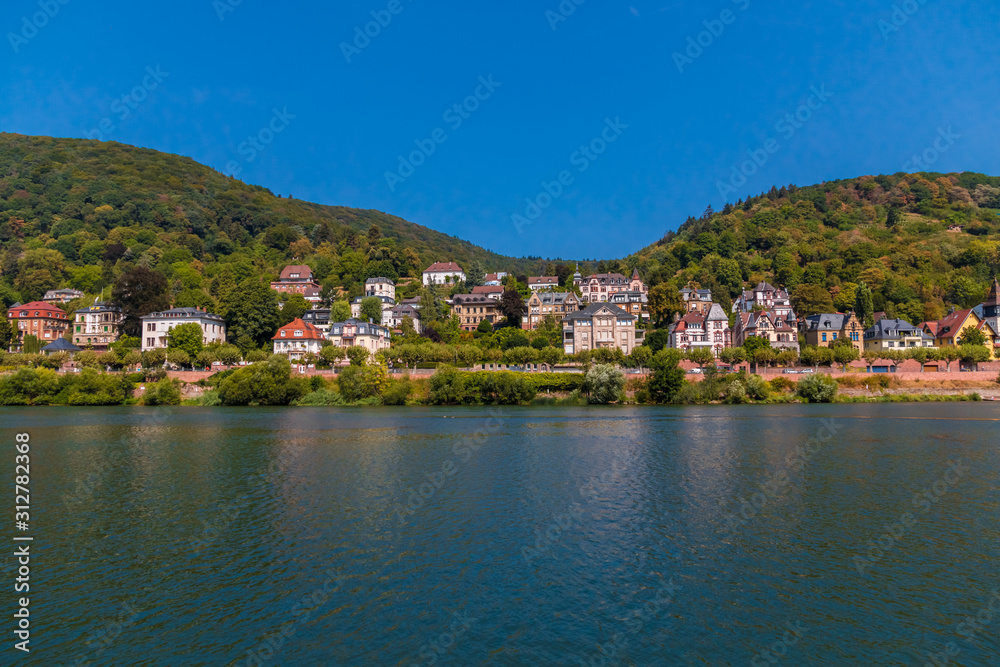 Lovely panoramic landscape view of the Heidelberg residential area with its beautiful mansions across the Neckar river on a nice summer day with a blue sky.