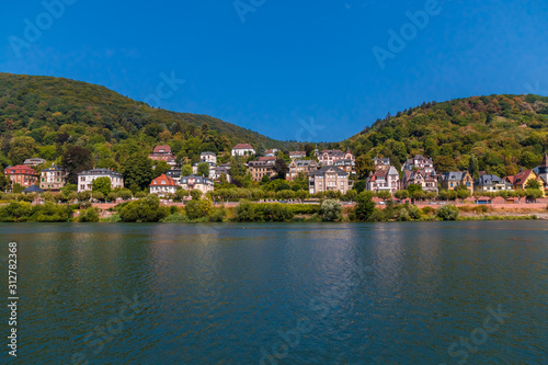 Fototapeta Naklejka Na Ścianę i Meble -  Lovely panoramic landscape view of the Heidelberg residential area with its beautiful mansions across the Neckar river on a nice summer day with a blue sky.
