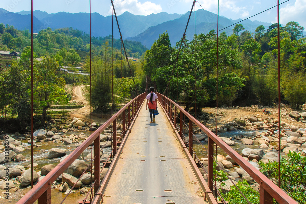Fototapeta premium A Hmong girl walking on a bridge across stream in Sapa, Vietnam 