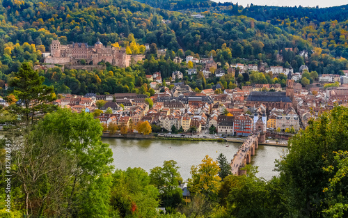 Close aerial panorama of Heidelberg's old town, the castle ruin on Königstuhl hill, the church Heiliggeistkirche and the Karl Theodor Bridge on Neckar river seen from the Philosopher’s Path in autumn.