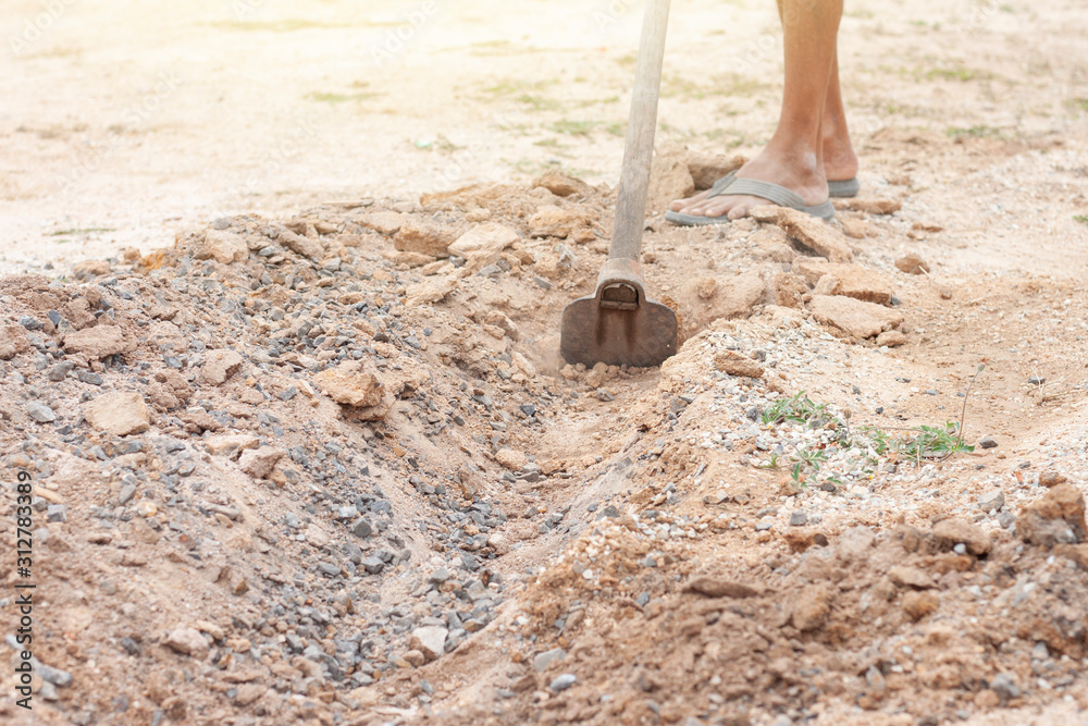 Fototapeta premium Digging the soil for making a small channel by a hoe.