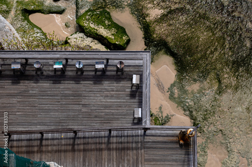 Aerial view of a decked seating area on a beach with a the sea coming in