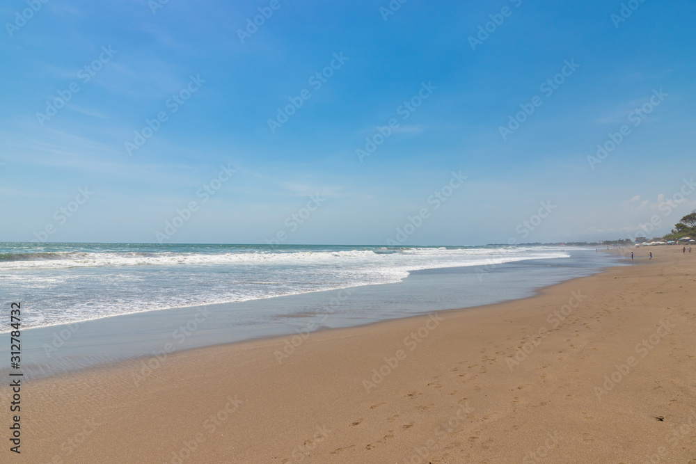 Seminyak beach. Wide sand beach with big waves, good for surfing; Bali island, Indonesia