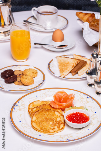 Breakfast in hotel, curd pancakes, cookies, orange juice, cup of coffee