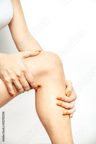 Acute pain in a knee joint, close-up image isolated on a white background. Hands touch the painful point Pain area of red color
