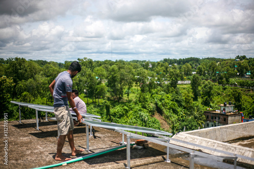 workers installing solar panels on the roof in cox's bazar