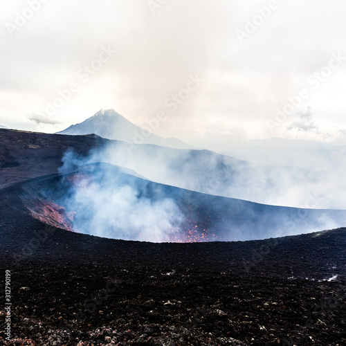 Crater of erupting volcano. Red hot lava flies from the vent of the volcano