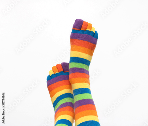 Female legs in colored socks raised to the top on a white isolated background