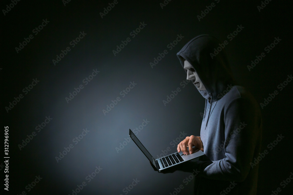 Professional hacker with laptop on dark background Professional hacker with laptop on dark background