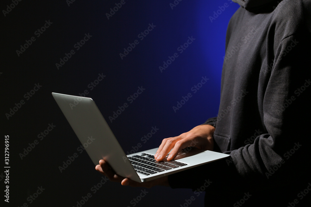 Professional hacker with laptop on dark background Professional hacker with laptop on dark background