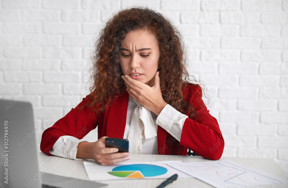 Worried African-American woman at table in office Worried African-American woman at table in office