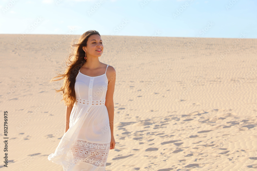 Beautiful woman with white dress walking on dunes in desert, Corralejo, Fuerteventura, Spain Beautiful woman with white dress walking on dunes in desert, Corralejo, Fuerteventura, Spain