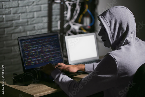 Professional hacker using laptop in dark room