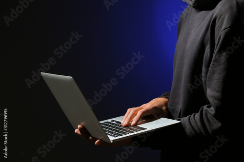 Professional hacker with laptop on dark background