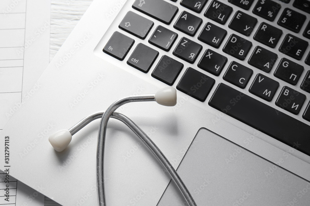 Modern stethoscope and laptop on table, closeup Modern stethoscope and laptop on table, closeup