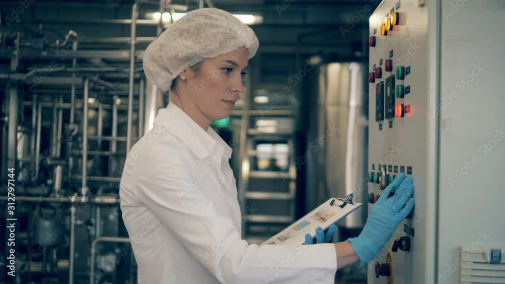 Woman, female factory engineer works with factory machine, checking it. Woman, female factory engineer works with factory machine, checking it.