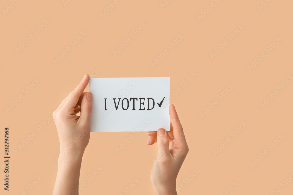 Hands holding paper with text I VOTED on color background Hands holding paper with text I VOTED on color background