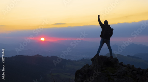 Mountaineer on top celebrating success with the sun at sunset over Gipuzkoa from Mount Jaizkibel  Euskadi