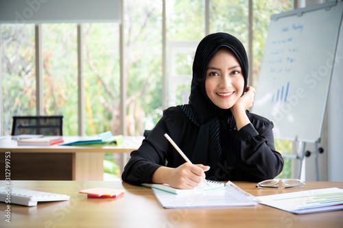 Portrait of smart beautiful Asian Muslim businesswoman working in the office, Diversity cultural and gender concept.